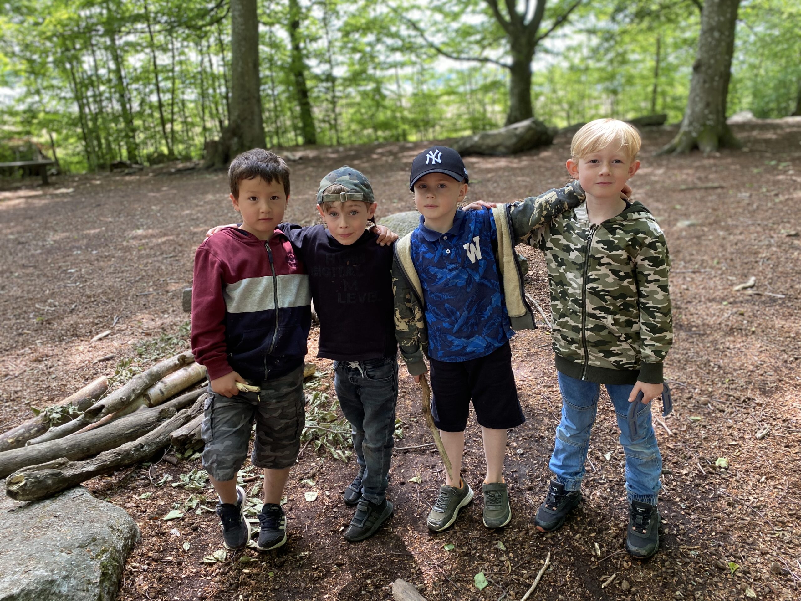 Bild på fyra barn som klättrar i ett när i skogen på skolgården.